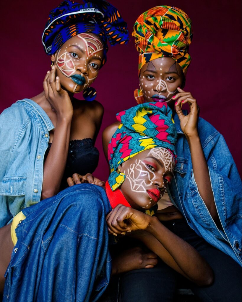 pexels-photo-2170387-2170387 Three women in colorful African outfits with face paint and headdresses celebrating culture.